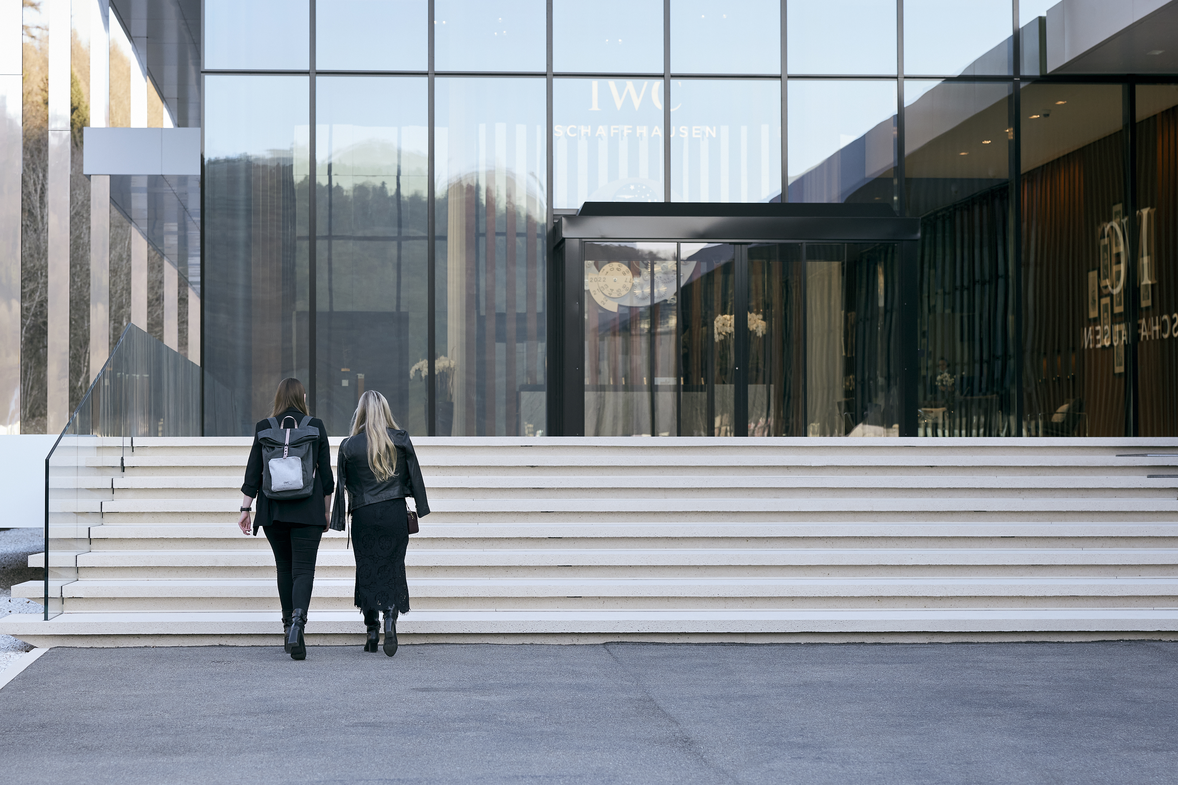 two women walking up stairs in front of a building