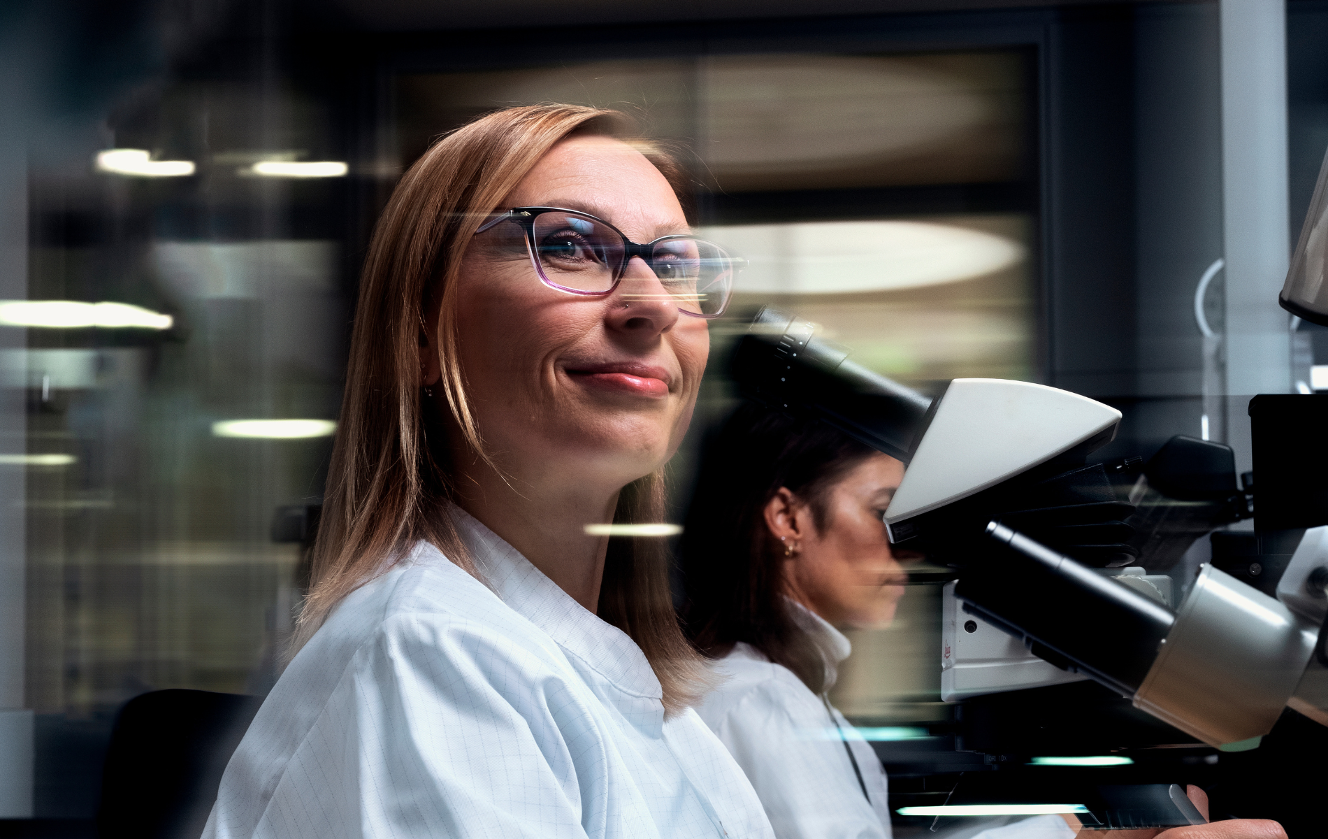 a person in a lab coat looking through a microscope