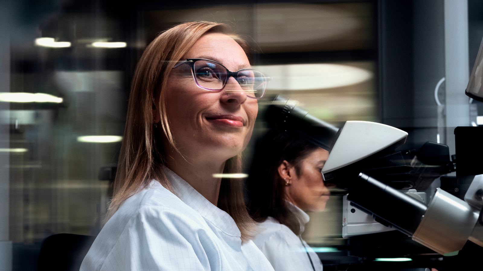 a person in a lab coat looking through a microscope
