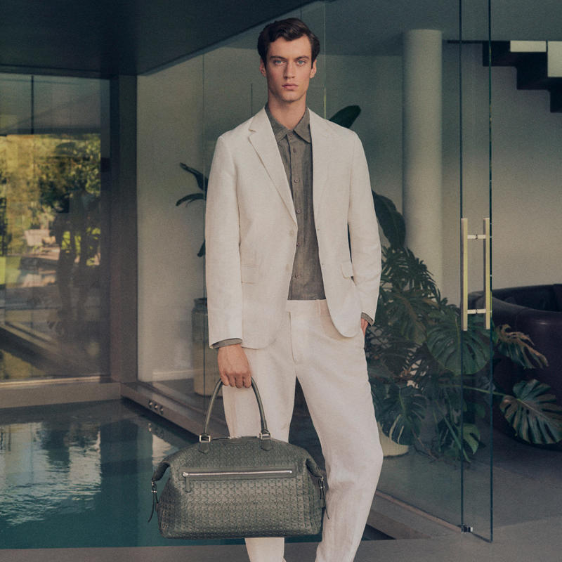 a person in a white suit holding a bag