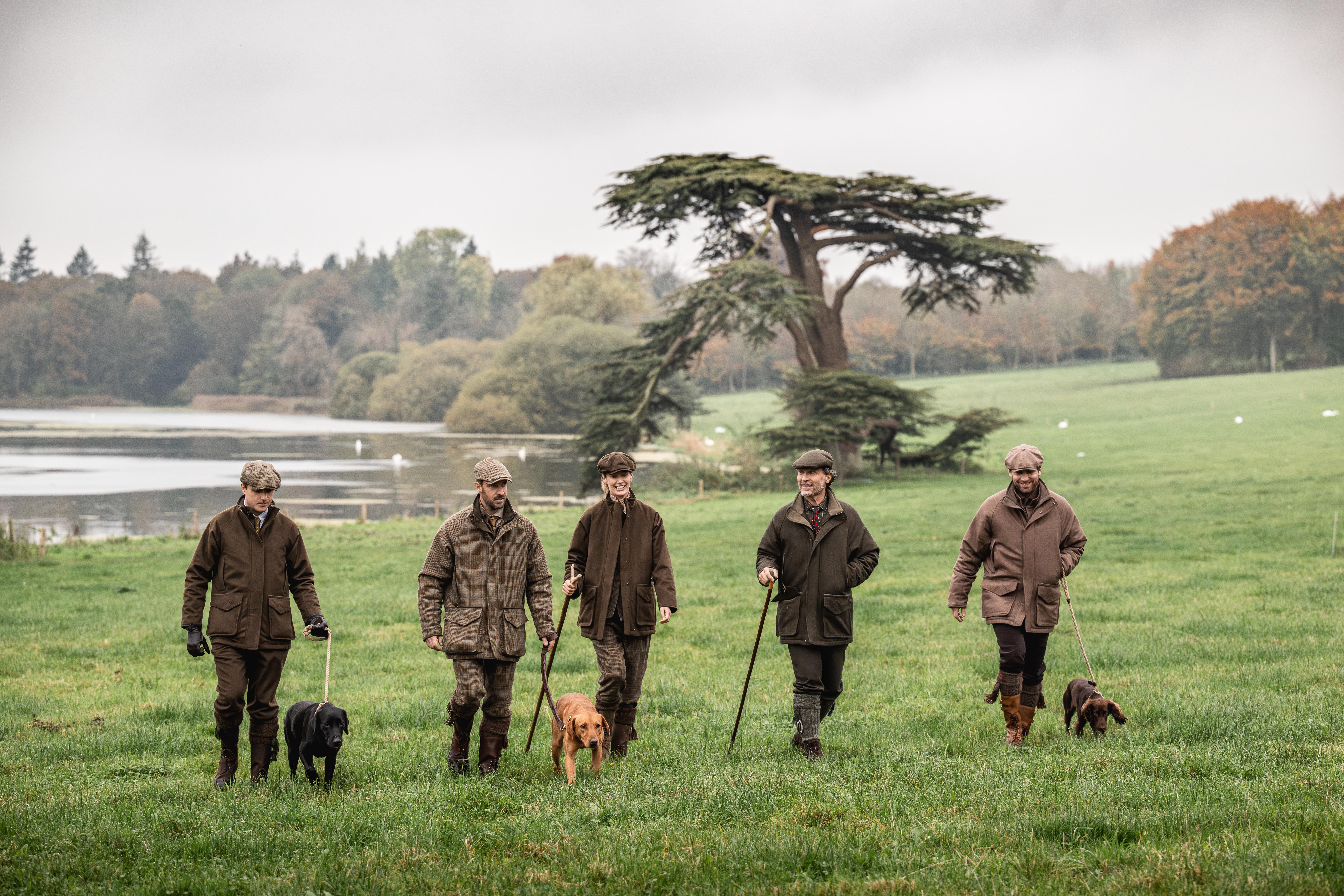 a group of men walking dogs in a grassy field