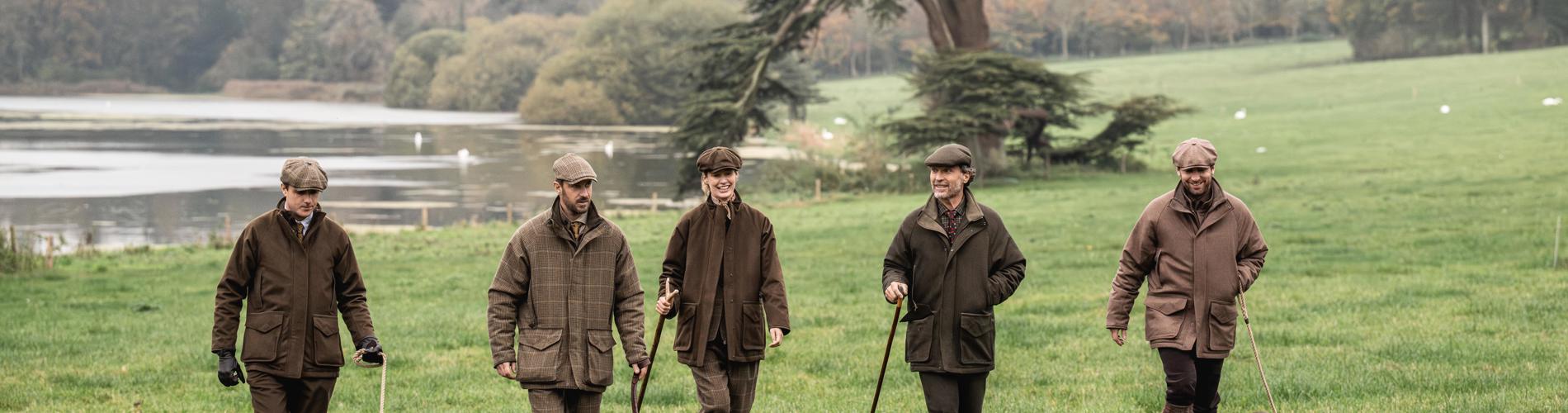 a group of men walking dogs in a grassy field