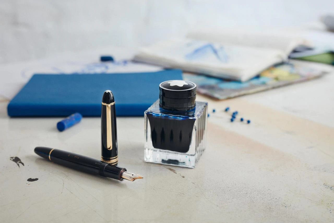 a fountain pen and ink bottle on a table